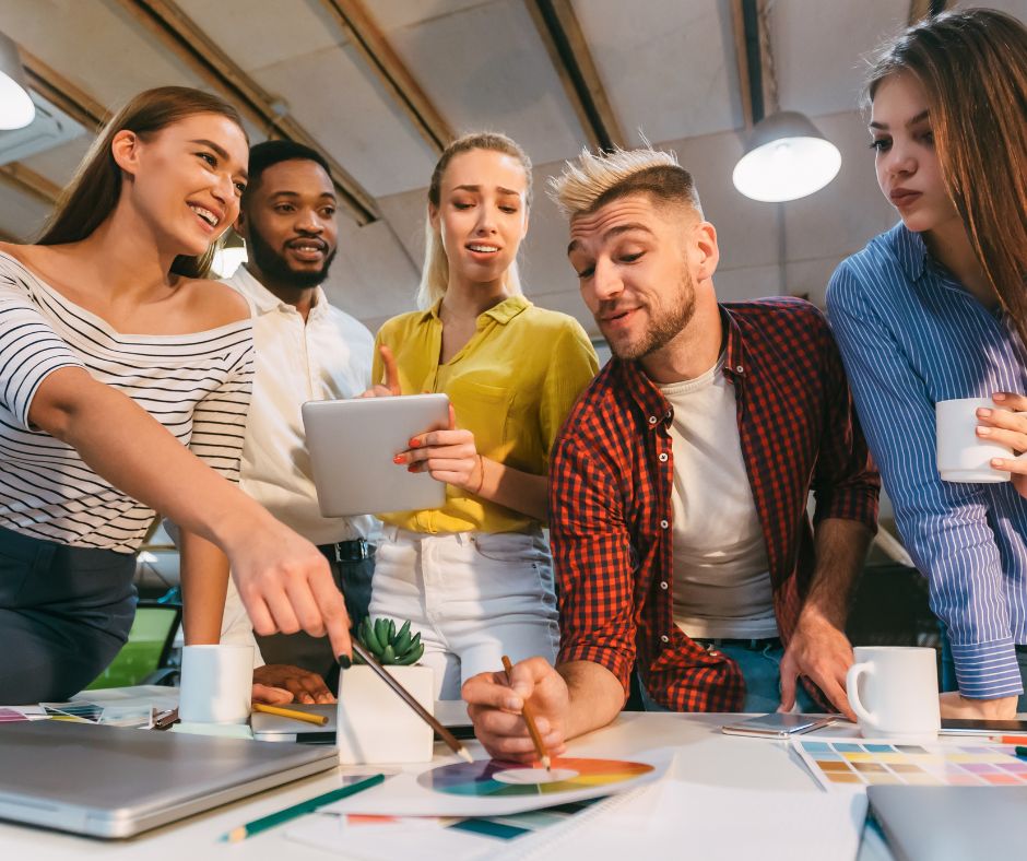 Group of diverse professionals collaborating on a design project in a modern office, showcasing creativity and teamwork.